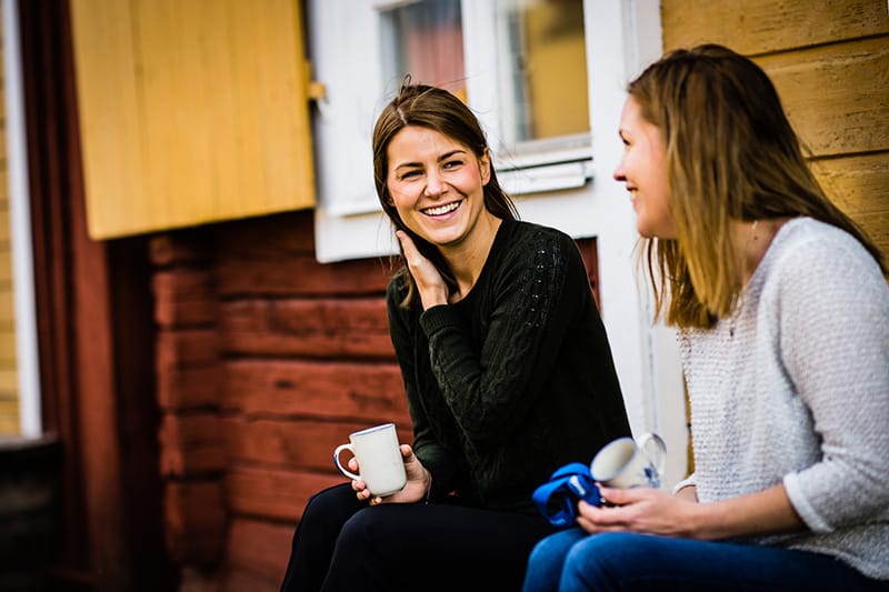 Two woman drinking coffee and talking to each other