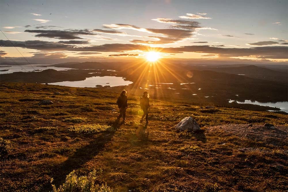 Couple walking on mountain in the midnight sun.